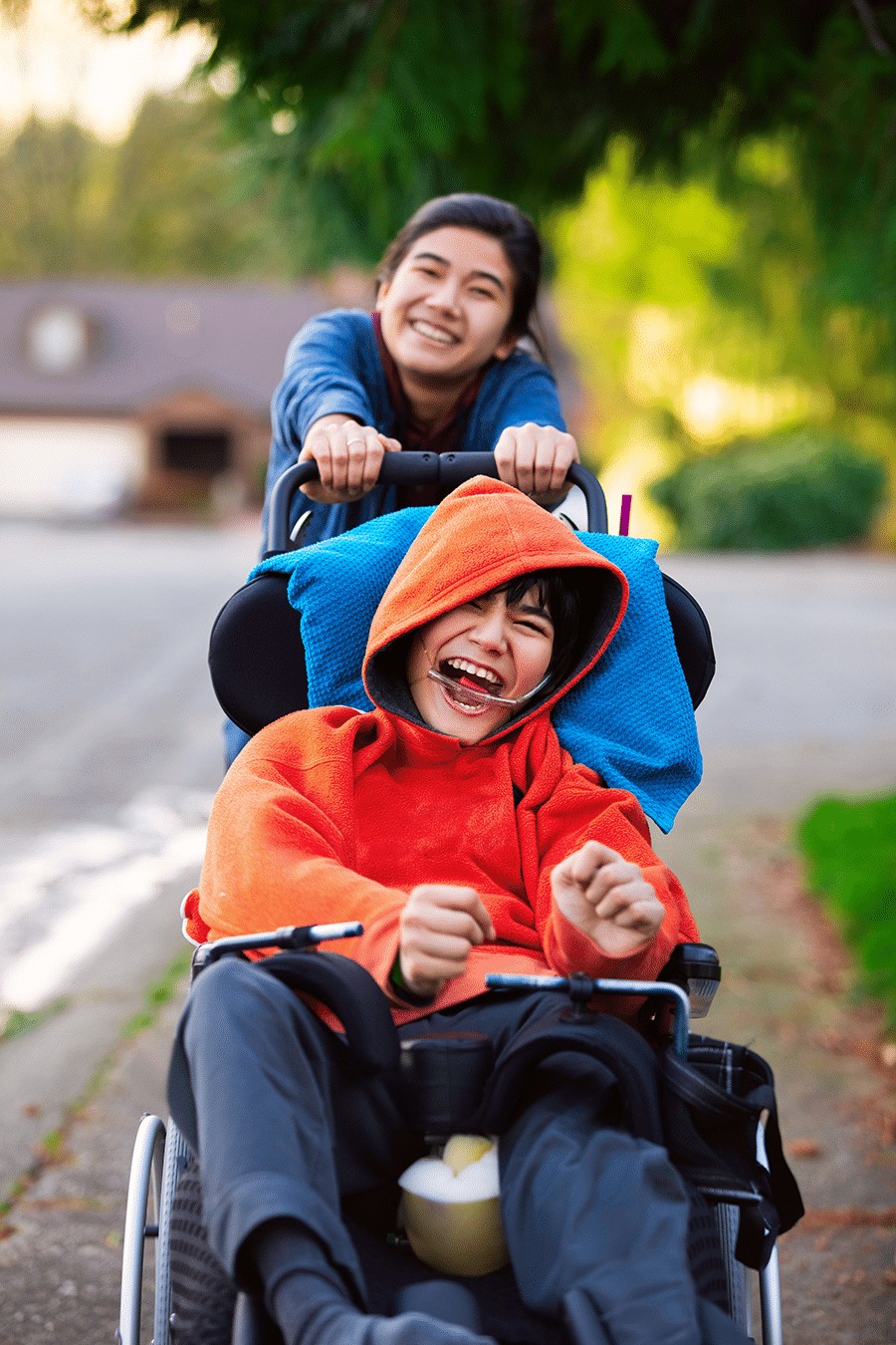 About Us 7 Stock image of Sister pushing disabled little brother in wheelchair around neighborhood